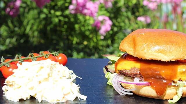 Cheeseburger mit BBQ-Sauce, Cole Slaw und Cherrytomaten im Garten.